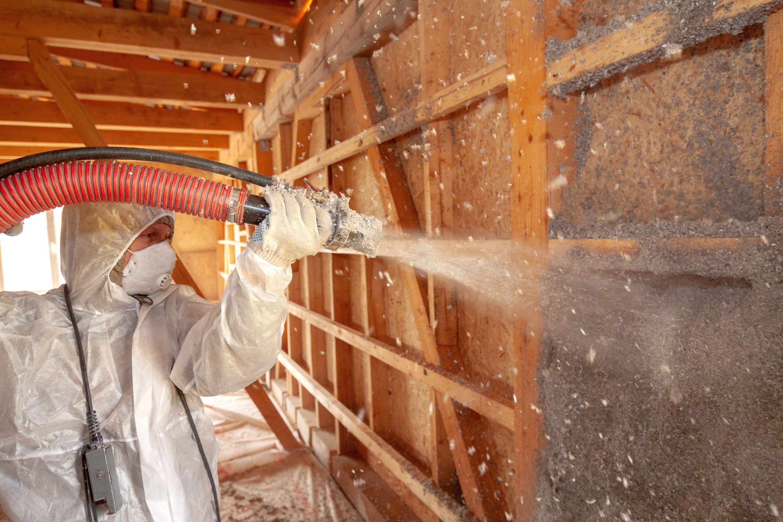 Spraying,Cellulose,Insulation,On,The,Wall man applying sprayed cellulose insulation to walls